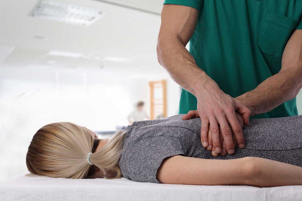 Person resting in a quiet room while a clinician evaluates neck movement during a migraine discussion.