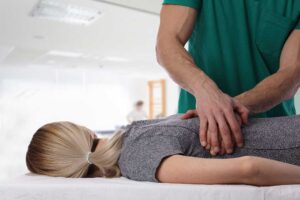 Person resting in a quiet room while a clinician evaluates neck movement during a migraine discussion.