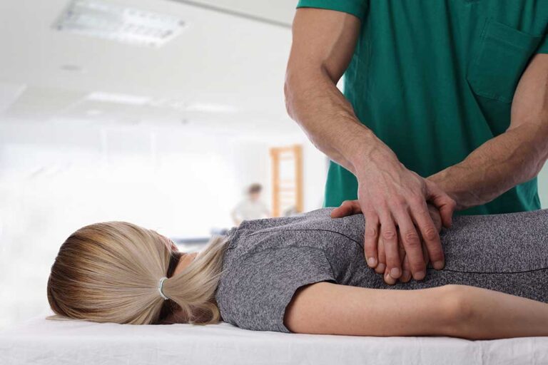 Person resting in a quiet room while a clinician evaluates neck movement during a migraine discussion.